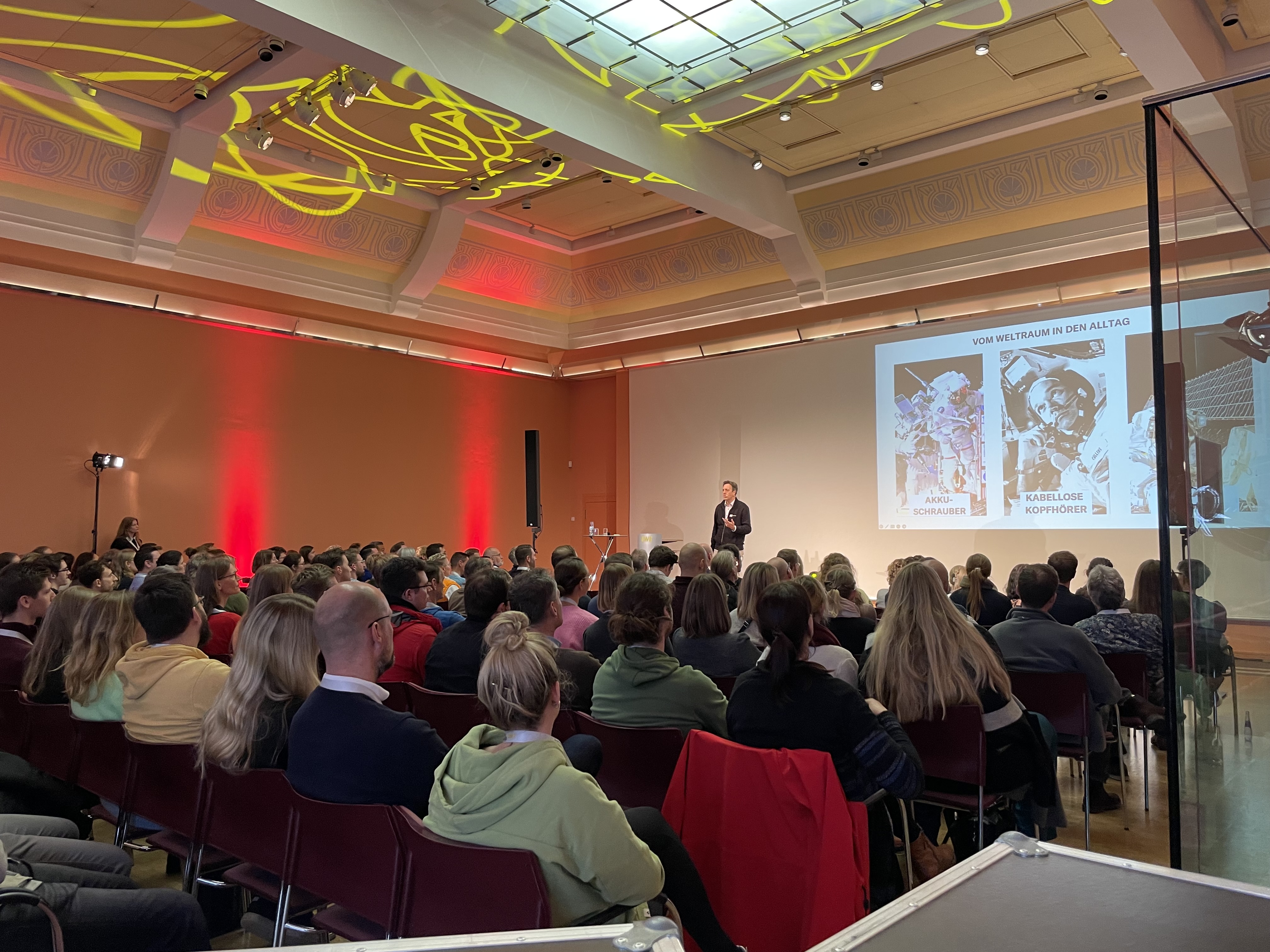 Roman Weishäupl auf großer Konferenzbühne vor mehreren hundert Zuhörern